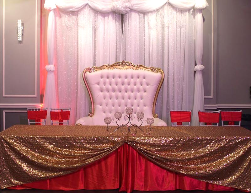 Crown Jewel Venue with red and gold Main table with beaded backdrop and white and gold throne chair